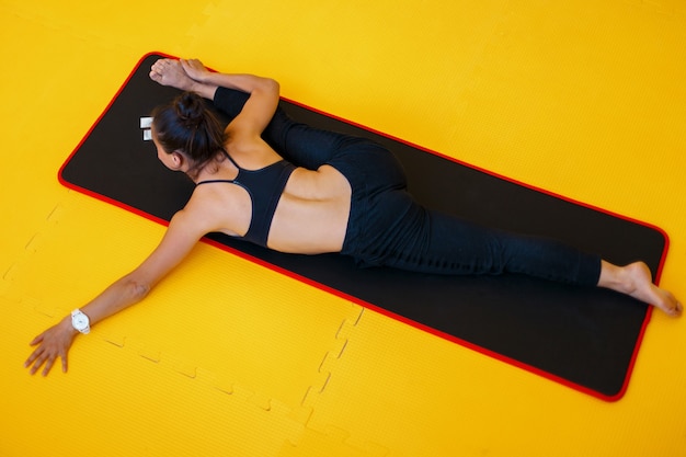 Jonge atletische vrouw beoefenen van fitness en het uitrekken op gele vloer doen