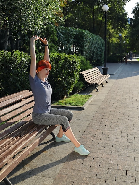 Foto jonge atletische vrouw uitoefenen zittend op een bankje