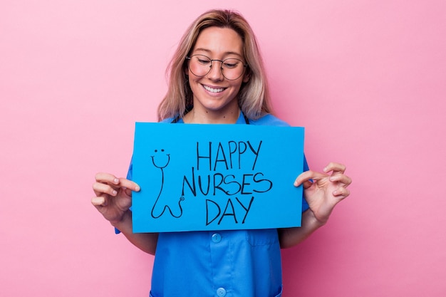 Jonge Australische verpleegstersvrouw die een aanplakbiljet van de internationale verpleegstersdag houden dat op blauwe achtergrond wordt geïsoleerd