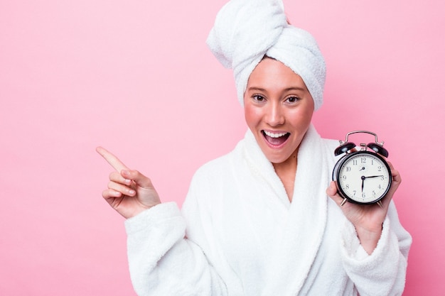 Jonge Australische vrouw verlaat de douche laat geïsoleerd op een roze achtergrond die naar de zijkant wijst