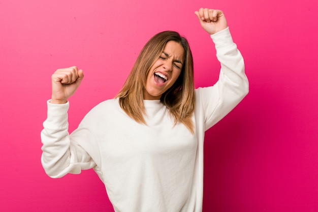 Jonge authentieke charismatische echte mensenvrouw tegen een muur die een speciale dag viert, springt en heft armen op met energie.