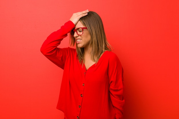 Jonge authentieke charismatische echte mensenvrouw tegen een muur die iets vergeet, voorhoofd met palm slaand en ogen sluitend.