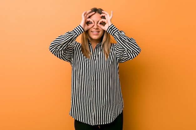 Jonge authentieke charismatische echte mensenvrouw tegen een muur die ok teken over ogen tonen