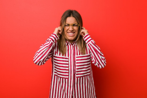 Jonge authentieke charismatische echte mensenvrouw tegen een muur die oren behandelen met handen.