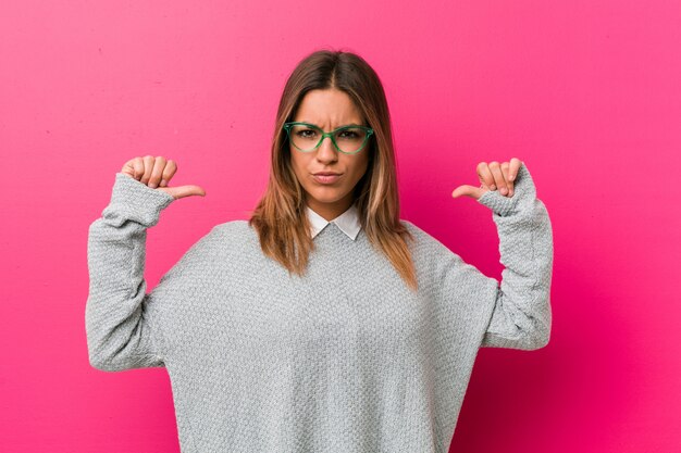 Jonge authentieke charismatische echte mensenvrouw tegen een muur voelt zich trots en zelfverzekerd, bijvoorbeeld om te volgen.
