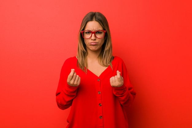 Jonge authentieke charismatische echte mensenvrouw tegen een muur waaruit blijkt dat ze geen geld heeft.