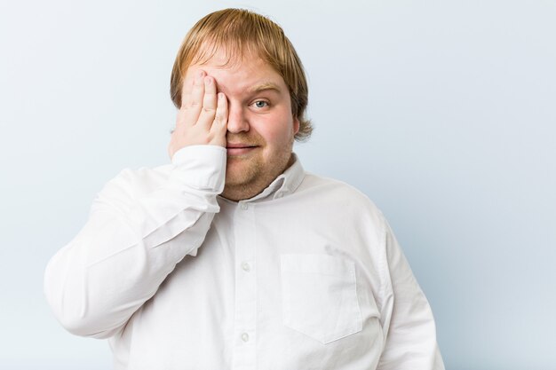 Jonge authentieke roodharige dikke man met plezier voor de helft van gezicht met palm.