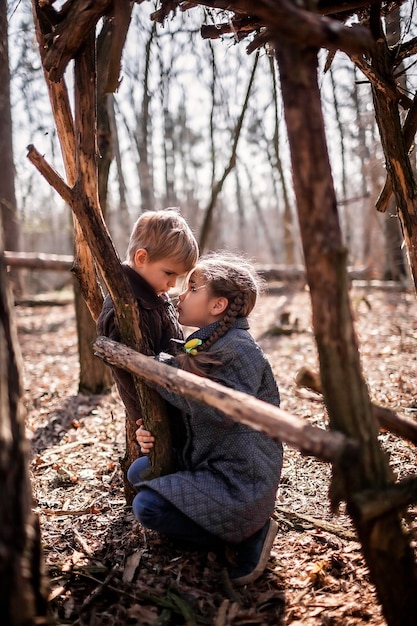 Jonge avonturiers bouwen een houten leefgebied in het wilde bos tijdens sociale wandelingen in de verte