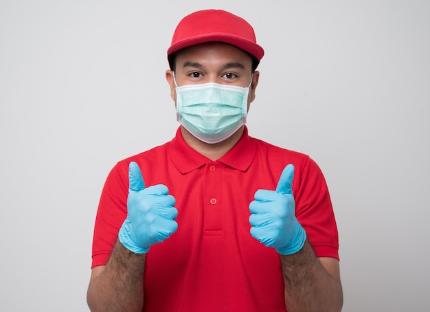 Jonge Aziatische bezorger in uniform dragen van beschermend masker en rubberen handschoenen