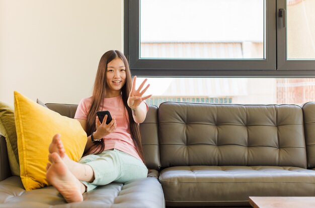 Jonge Aziatische en vrouw die vriendelijk glimlacht kijkt, nummer vier of vierde met vooruit hand toont, aftellend