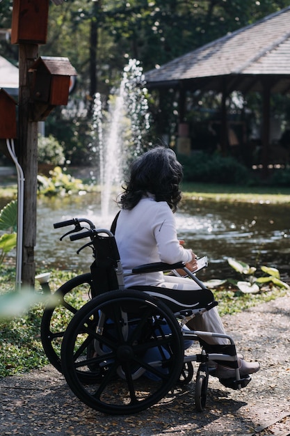 Jonge aziatische fysiotherapeut die met een oudere vrouw werkt aan het lopen met een rollator