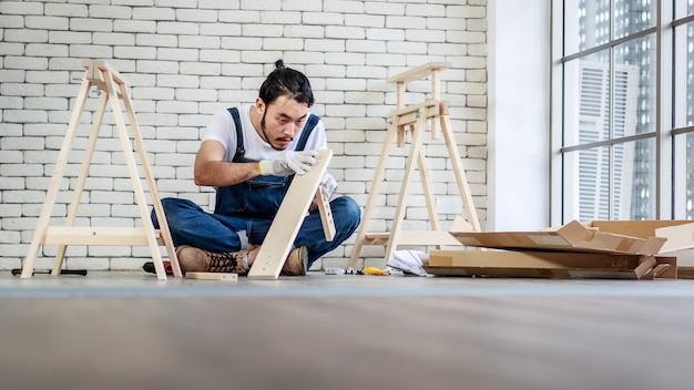 Jonge Aziatische hipster man aan het werk als klusjesman, houten tafel monteren met apparatuur.
