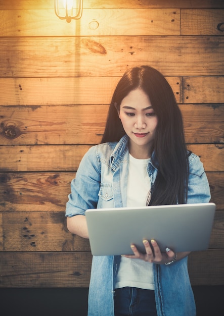 Jonge Aziatische hipstervrouw die laptop computer met behulp van