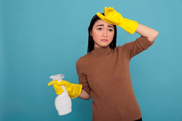 Jonge aziatische huisvrouw gestrest van het dagelijkse werk met wasmiddel in gele rubberen handschoen Schoonmaakconcept, gefrustreerd overwerkt dienstmeisje met negatieve gemoedstoestand