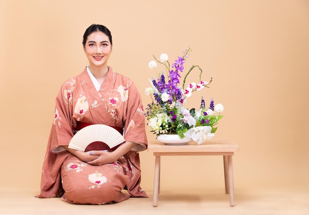 Jonge Aziatische Japanse vrouw uit de jaren '20 draagt traditionele Kimono en doet Ikebana-bloemstuk