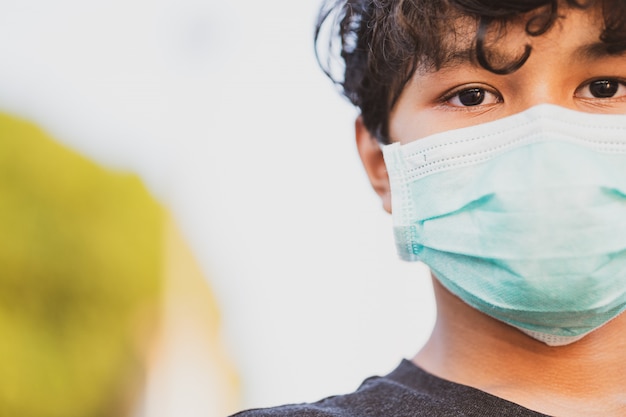 Jonge Aziatische jongen die een beschermend masker, vrees voor griep en coronavirus draagt