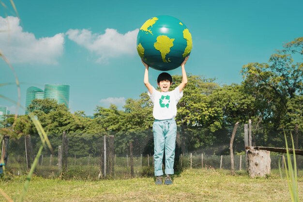 Foto jonge aziatische jongen met grote planeet earth globe in natuurpark met hemelachtergrond als dag van de aarde om deze planeet te redden met esg-principe en milieuvriendelijke energie voor een betere toekomst gyre