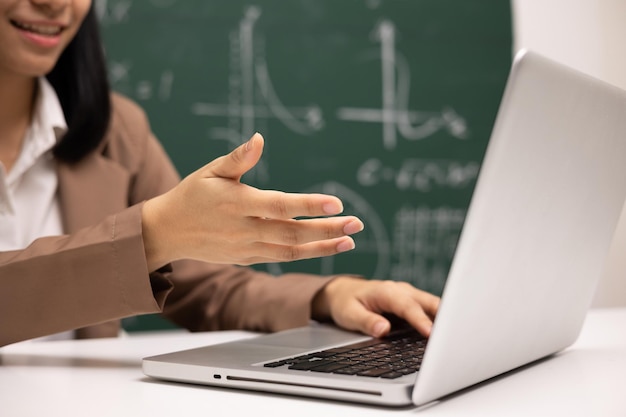 Jonge Aziatische leraar vrouw zit met behulp van laptop videoconferentie met student Vrouwelijke leraar die de wiskunde in de klas traint vanuit livestream met computer online cursus