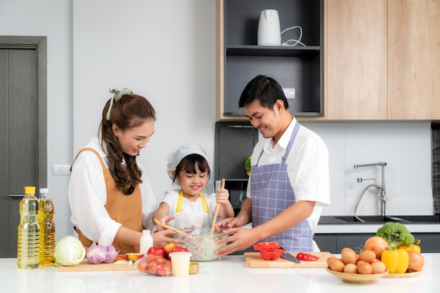 Jonge Aziatische liefdesfamilie bereiden salade groente op tafel in de keuken