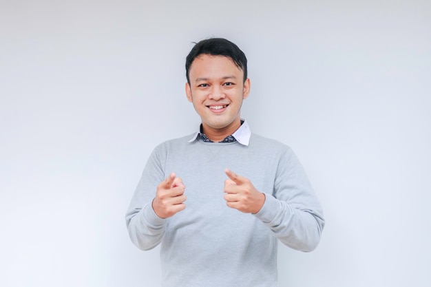 Jonge Aziatische man draagt een grijs shirt met een blij lachend gezicht en duimen omhoog of ok teken