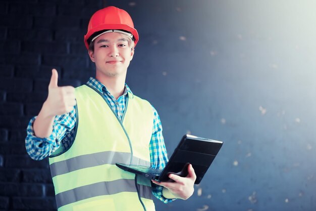 Jonge Aziatische man in beschermende helm en bouwvest