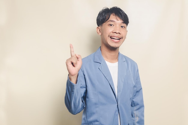 Jonge aziatische man in collegekostuum met lege ruimte van tanden op geïsoleerde achtergrond