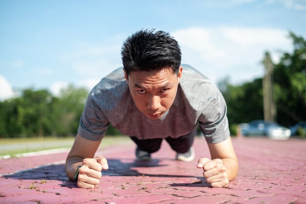 Jonge Aziatische man in sportkleding push-ups doen