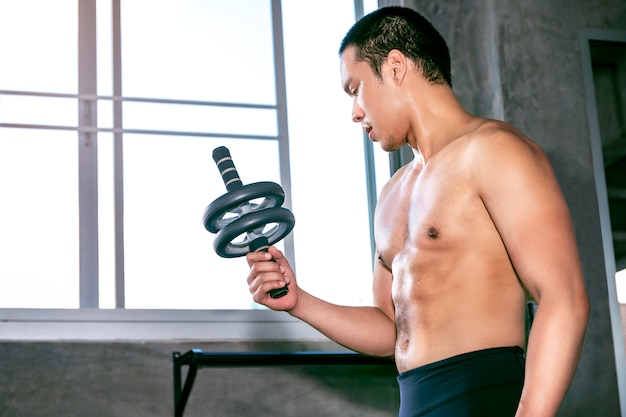 Jonge Aziatische man in sportkleding training buikspieren met fitness wiel op fitness gym.