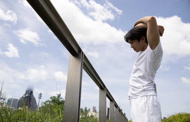 Jonge Aziatische man in wit overhemd stretch lichaam in park Concept voor gezondheid levensstijl in park