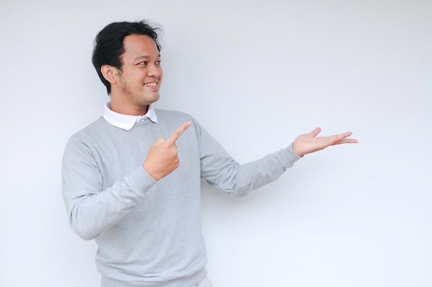 Jonge Aziatische man lacht en is blij met zijn hand op lege ruimte
