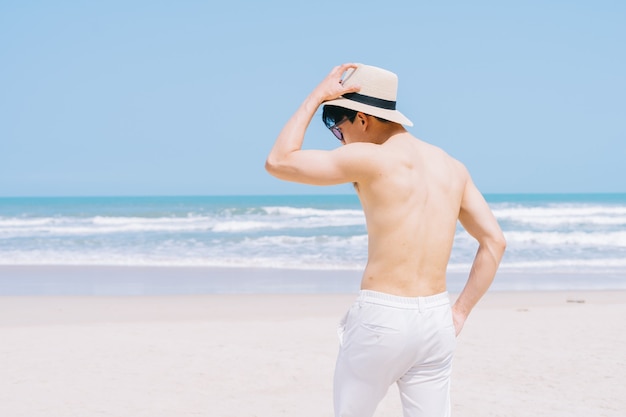 Jonge aziatische man lopen op het strand