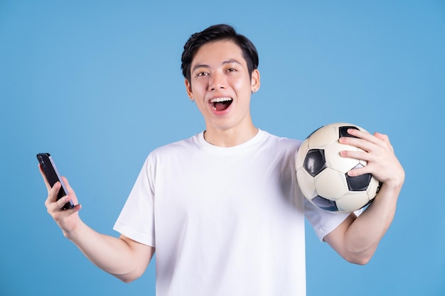 Jonge Aziatische man met bal op achtergrond
