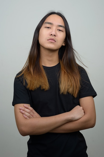 Jonge Aziatische man met lang haar met gekruiste armen