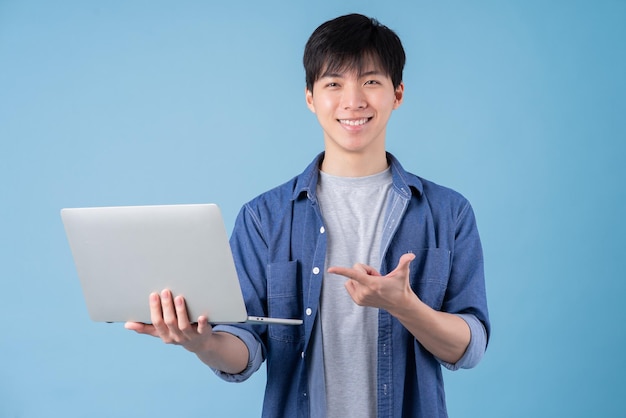 Jonge aziatische man met laptop op blauwe achtergrond