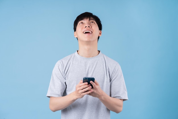 Jonge Aziatische man met smartphone op blauwe achtergrond