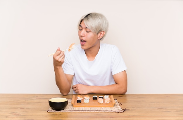 Jonge Aziatische man met sushi in een tafel