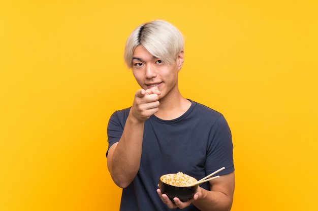 Jonge Aziatische man over geïsoleerde gele punten vinger naar je met een zelfverzekerde uitdrukking