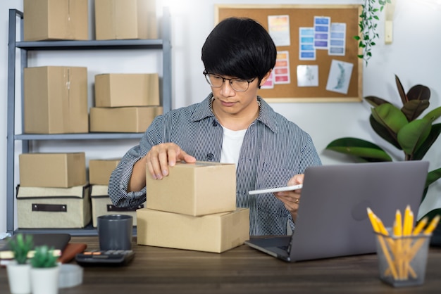 Jonge Aziatische mens die aan het bureau van de leveringsdienst werken