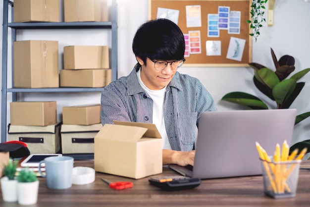 Jonge Aziatische mens die aan het bureau van de leveringsdienst werken