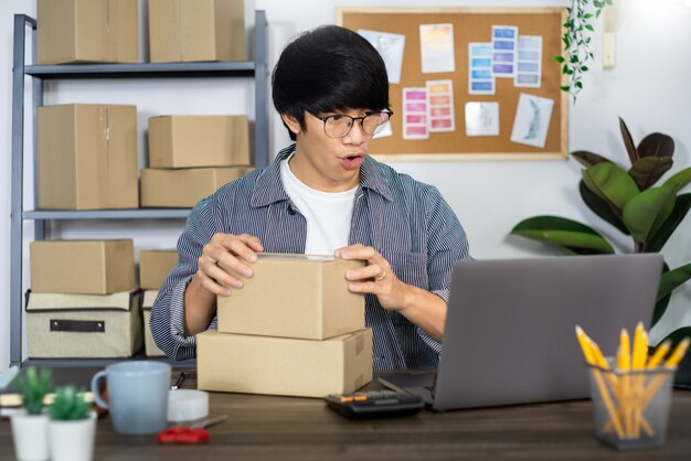 Jonge Aziatische mens die aan het bureau van de leveringsdienst werken