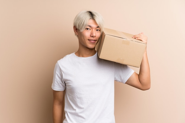 Jonge Aziatische mens over geïsoleerd houdend een doos om het naar een andere plaats te verplaatsen