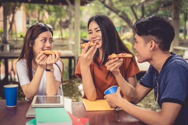 Jonge Aziatische mensen vieren met de pizza in de hand. Voedsel en vriendschap concept. Leefstijlthema