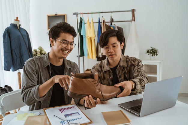 Jonge Aziatische mensenzakenman die over product van schoenen babbelt