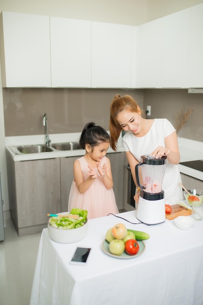 Jonge Aziatische moeder en dochter die versgeperste tomatensmoothies maken dochter is erg blij