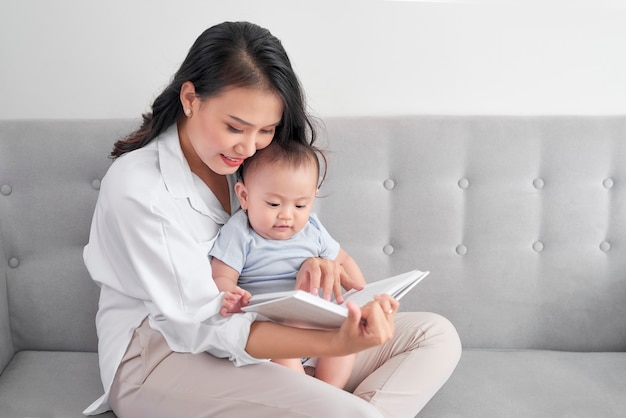 Jonge Aziatische moeder leesboek aan baby. Zoet moment.