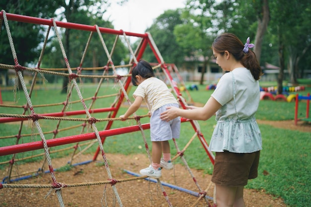 Jonge aziatische moeder speelt met haar baby op de speelplaats moeder en dochter schattige babydochter speelt met moeder gelukkig grappig familieconcept