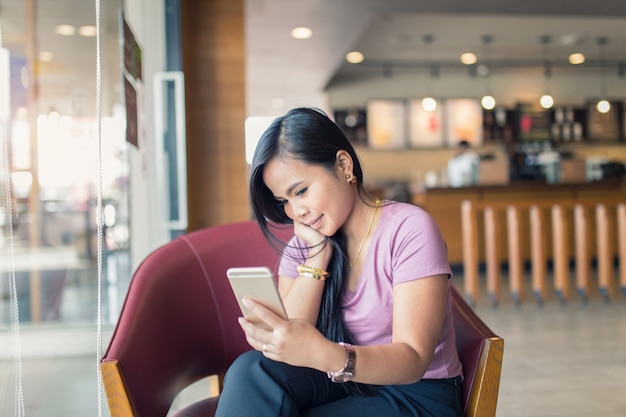 Jonge Aziatische mooie vrouw met behulp van slimme telefoon in koffie winkel.