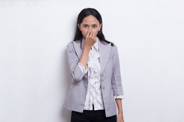 Jonge aziatische mooie zakenvrouw die haar neus vasthoudt vanwege iets dat slecht ruikt