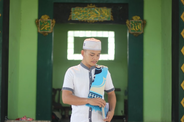 Foto jonge aziatische moslim die in de moskee bidt die een gebedsmat draagt