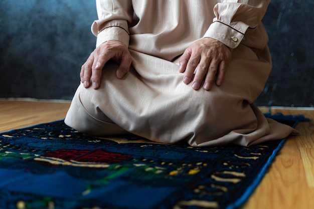 Jonge Aziatische moslimman bidt thuis op het gebedskleed op Ramadan Kareem